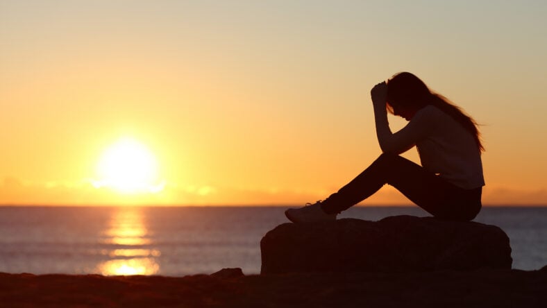 Sad woman silhouette worried on the beach