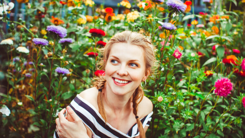 Woman in a summer garden in a dress among flowers