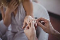 Man putting engagement ring on woman's hand