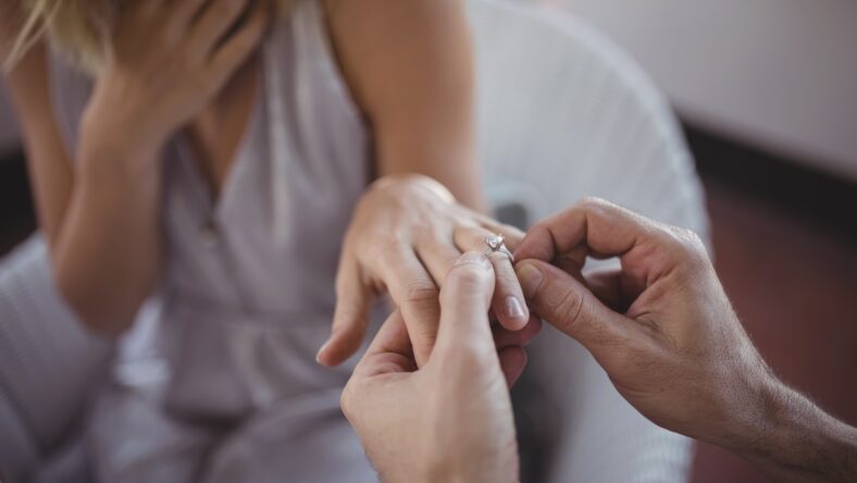 Man putting engagement ring on woman's hand