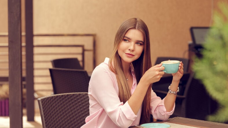 Young woman drinking coffee in a cafe outdoors