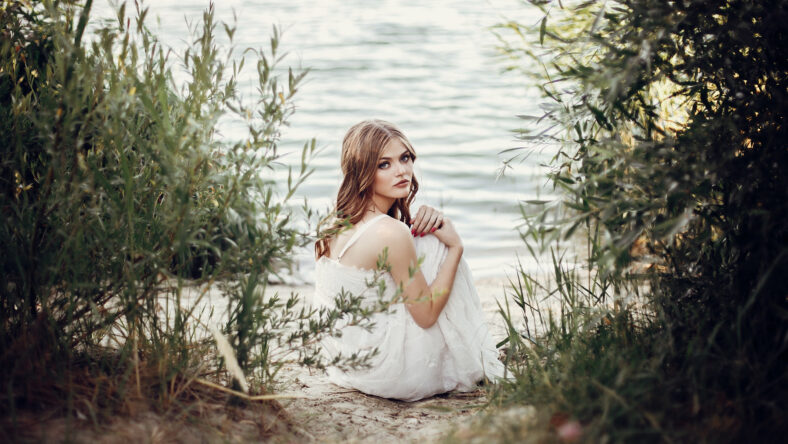 beautiful boho girl sitting on sandy beach