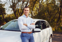 A smiling man with crossed arms stands