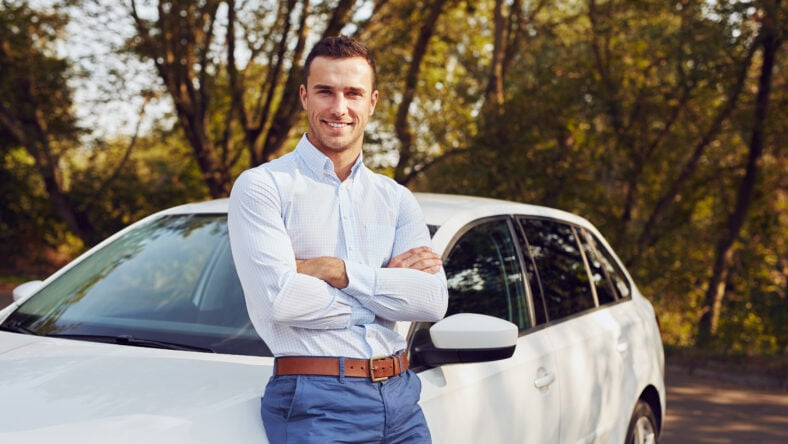 A smiling man with crossed arms stands
