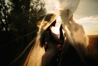 Beautiful wedding couple portrait behind veil. Sunrise