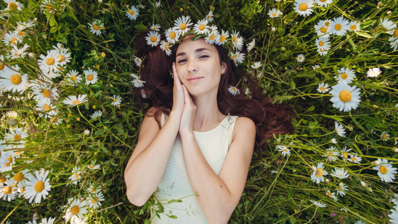 The beautiful woman lies in the field of chamomiles. . Carefree happy brunette woman with healthy long hair having fun outdoor in nature. harmony concept