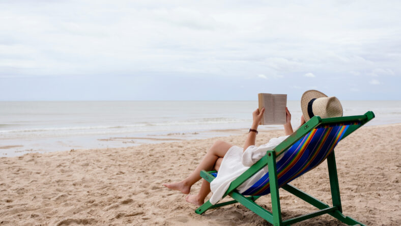 A beautiful woman lying down and reading book on the beach chair with feeling relaxed