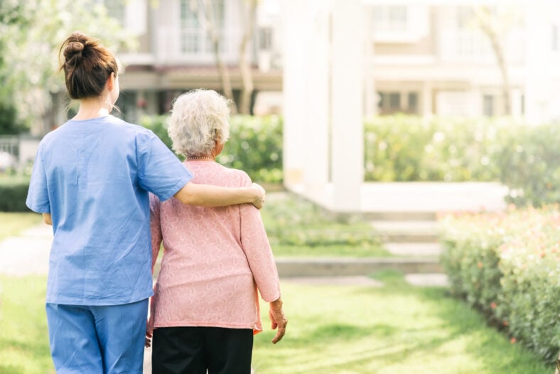 Back view of nurse caregiver support walking