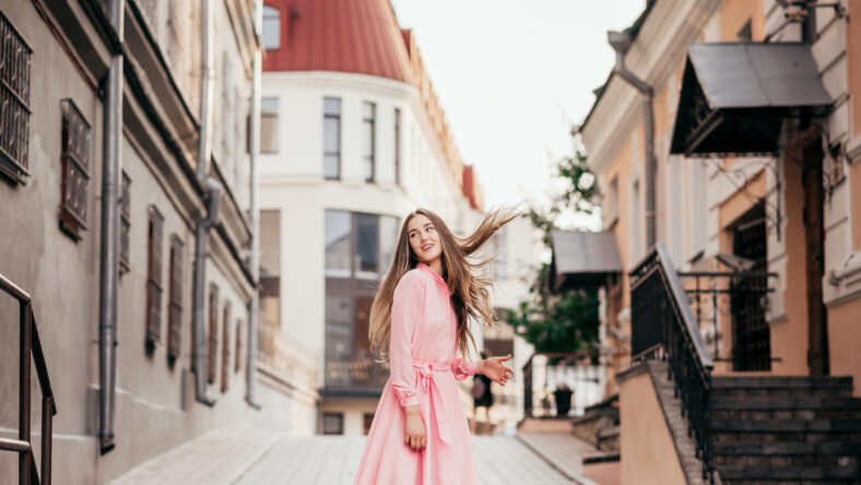 A young, beautiful girl in a pink dress walks through the beautiful streets in the city. Photo close - up and General plan. Very beautiful portraits of a girl in the city.