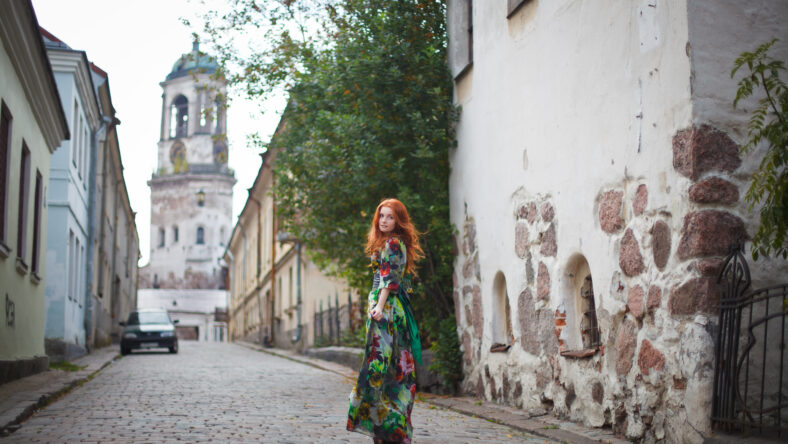 beautiful red-haired girl walks along the old streets of Vyborg