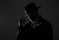 Old fashioned detective in hat on dark
