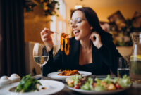 Young woman eating pasta in a cafe
