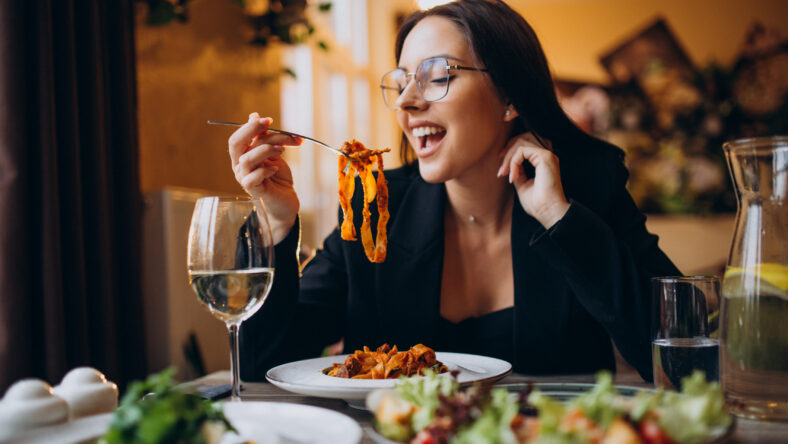 Young woman eating pasta in a cafe