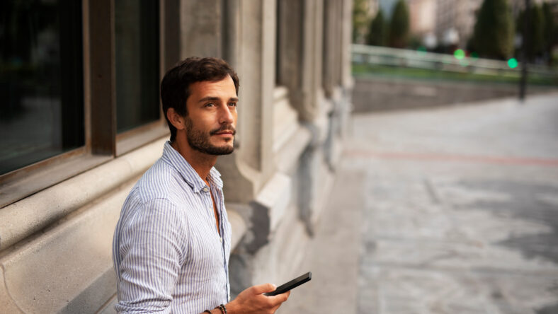 Young stylish man using the phone outdoors.