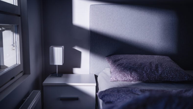 Bed at night in dark bedroom. Blue