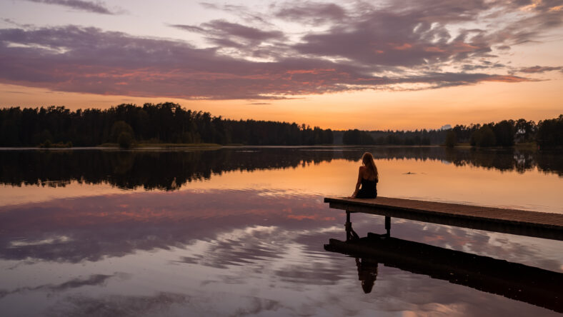Lonely girl silhouette at sunset by the