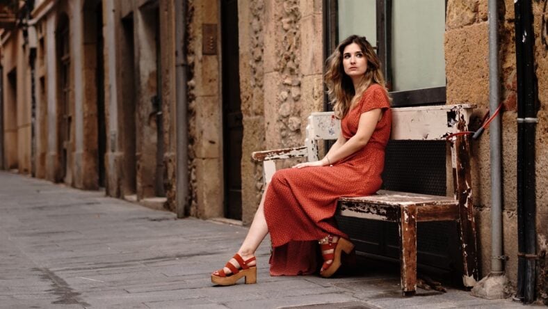 young woman sitting on street bench