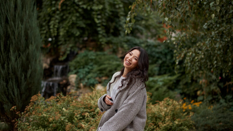 Close-up portrait of beautiful pretty asian kazakh brunette woman in plaid coat with charming smile walking along outdoors in park. Happy face. Autumn season. Cozy.