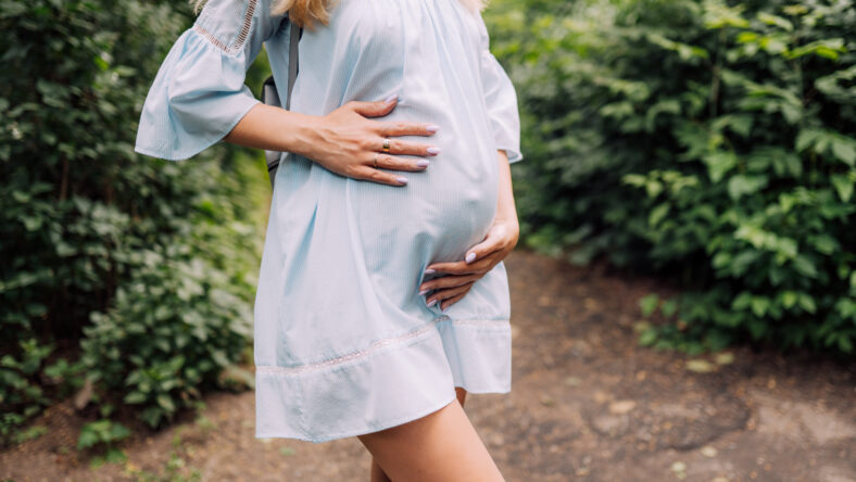 Close up of pregnant belly in nature.