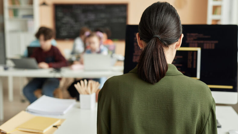 Back view at female teacher using computer