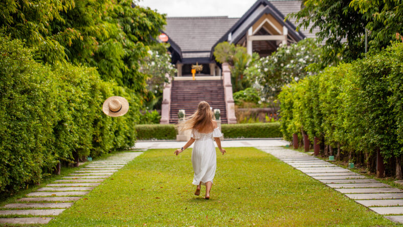 Young woman walking towards house on garden