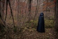 Scary figure in black mantle in the