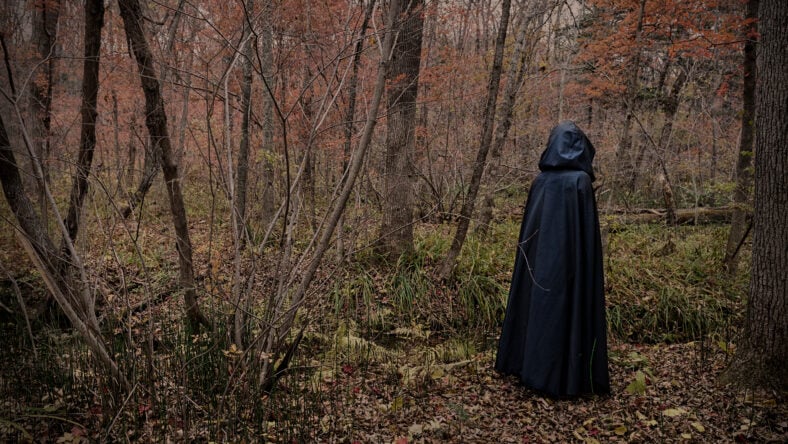 Scary figure in black mantle in the