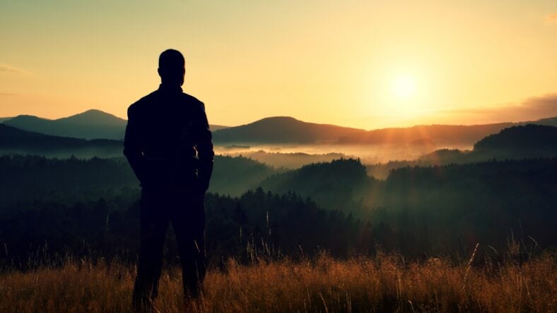 Tall hiker stand on meadow with golden