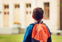 Boy with rucksack infront of a school