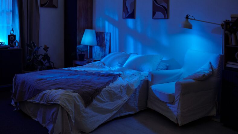 Empty bedroom with unmade bed and armchair