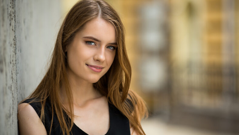Attractive young girl standing oitdoors. View of