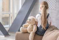 Lonely little girl with teddy bear in