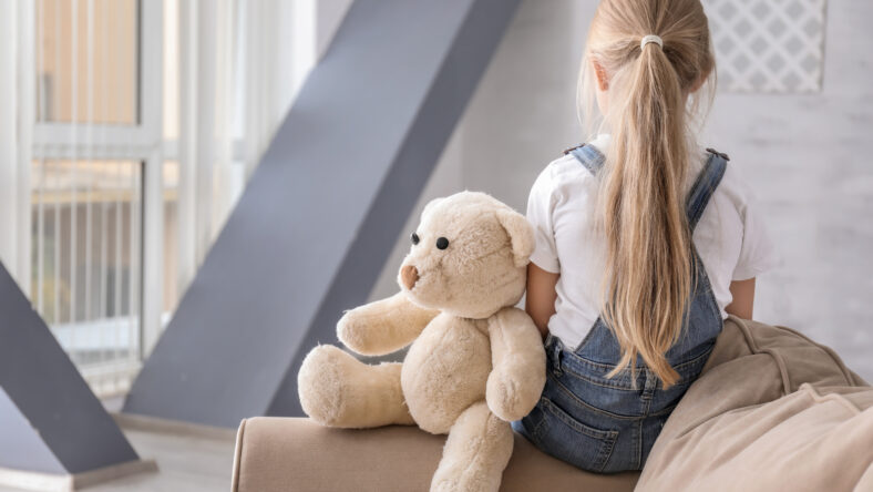 Lonely little girl with teddy bear in