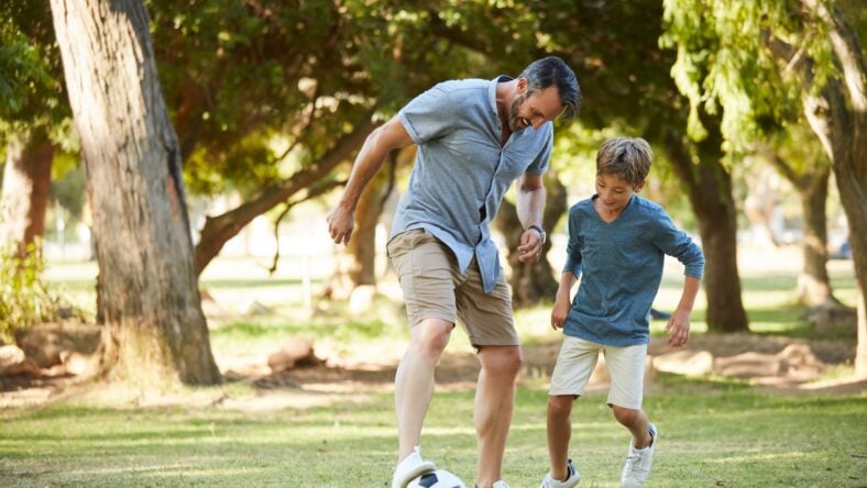 Father, boy and play with football at