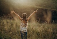 Little girl standing with raised arms in