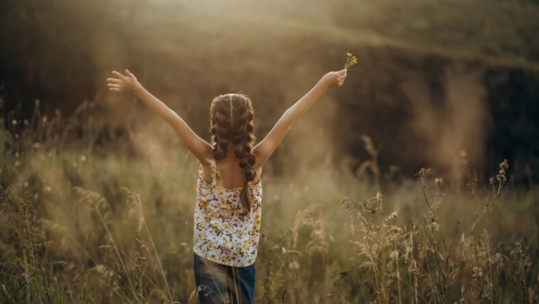 Little girl standing with raised arms in