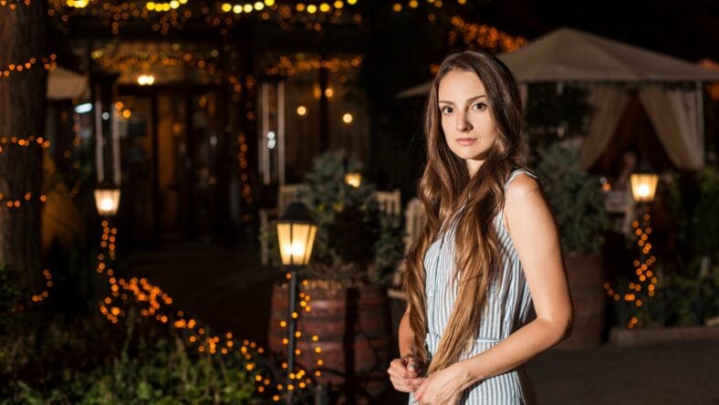 young attractive woman stands near the restaurant.