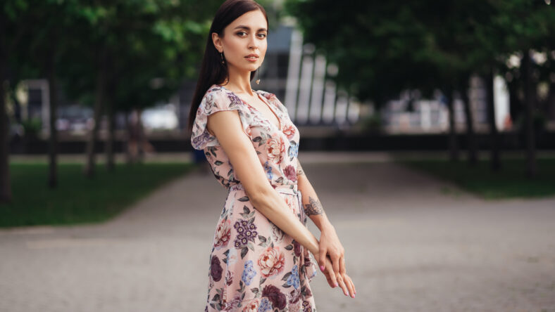 Beautiful girl in pink dress with flowers posing outdoors on summer day. Fashion city photo