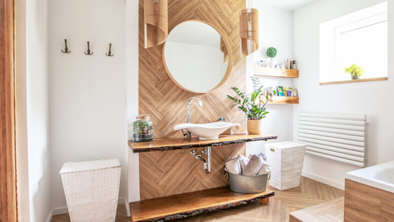 White sink on wood counter with a round mirror hanging above it. Bathroom interior.