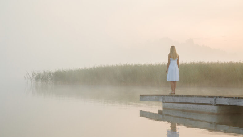 Young woman in white dress standing alone