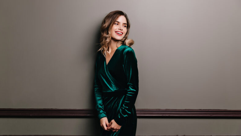 Winsome girl with elegant hairstyle preparing for party. Indoor portrait of stunning woman in long velvet dress.
