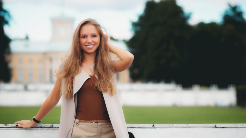 portrait of young smiling attractive caucasian woman in stylish summer outfit in the park
