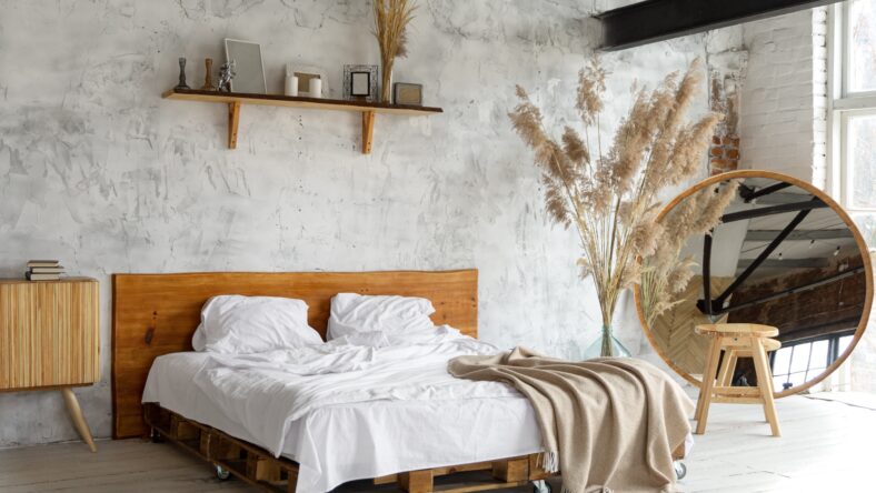 Spacious airy white eco style loft bedroom with bed, mirror and pampas grass decoration