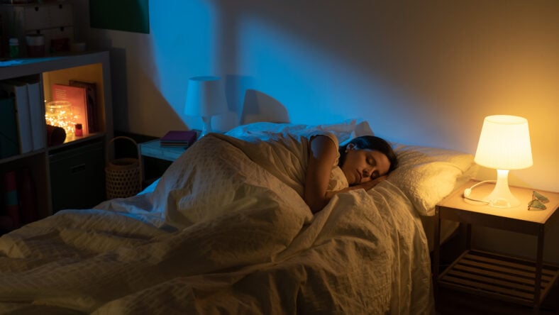 Beautiful girl suffering from insomnia lying in her bed with Blue Colors from the moon. High quality photo