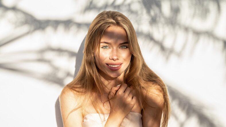 Lovely beautiful young blonde woman with natural freckles smiling to the camera. Natural shadows. A lot of copy space.