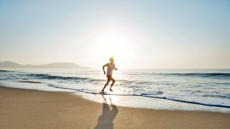 Young man running along beach in the