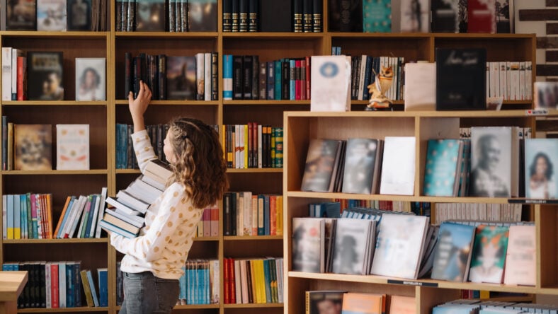Teen girl among a pile of books.