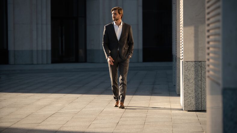 Elegant handsome man in classic suit standing near the office building