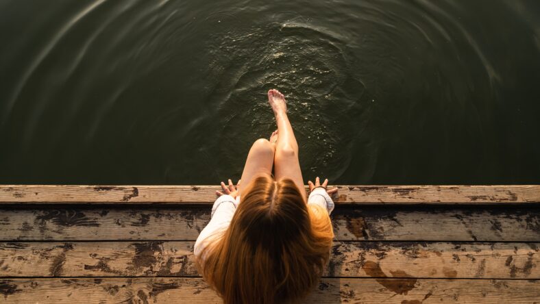 Woman relaxes by the lake sitting on
