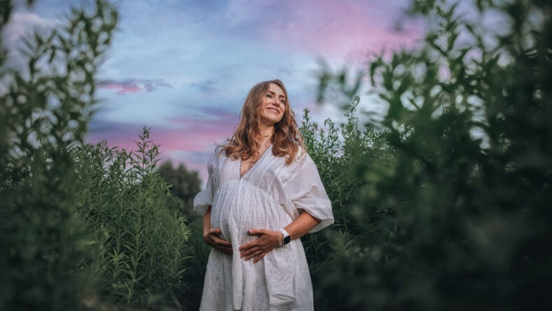 Pregnant woman in white boho summer dress